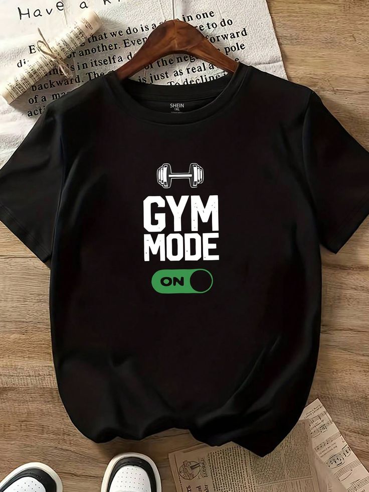 Black t-shirt with 'GYM MODE ON' text on a wooden surface