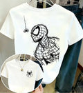 White short-sleeve graphic T-shirt hanging on a hanger, featuring a large black sketch-style spider-themed print on the front and a smaller black spider logo on the left chest. A circular inset shows a close-up of the chest print and a necklace worn with the shirt.